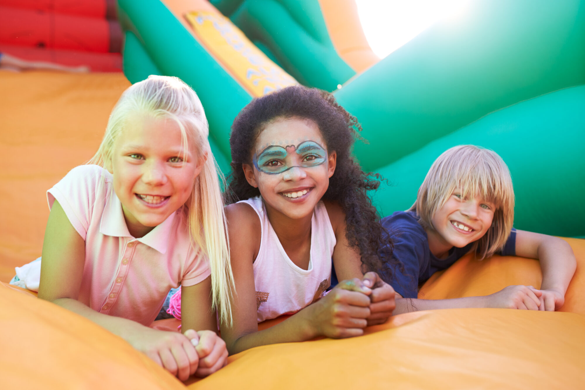 Portrait,Of,Children,On,Inflatable,Slide,At,Summer,Garden,Fete